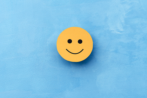 Yellow smiley face on a blue background. The concept of positive mood. Emotions and feedback.