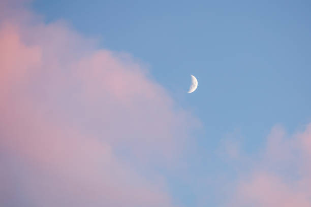 istock Half moon white on a blue sky with pink clouds 1364157645