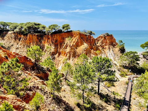 The awe-inspiring red limestone coast at Lagos, Algarve, Portugal .Scenic Algarve coast seascape with red rocks, cliffs and green shrubs, Portugal, Europe