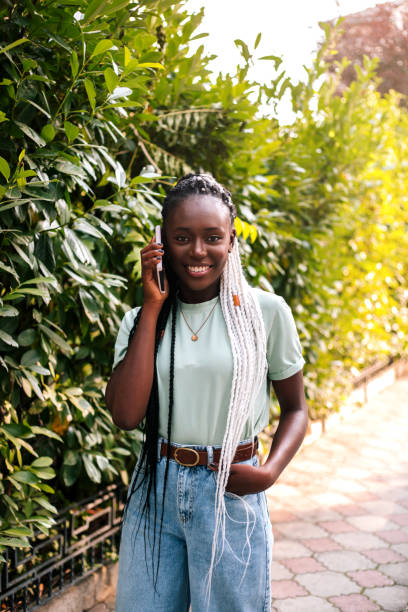 istock Beautiful black woman using smartphone at street. 1364159347