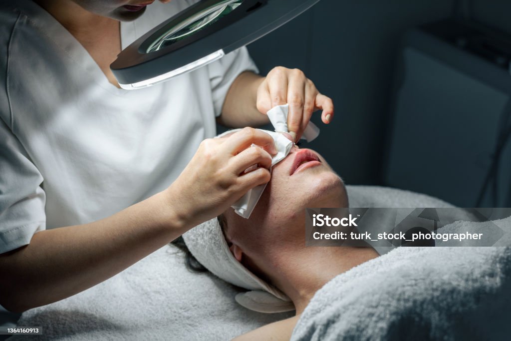Dermatologist doing facial care against acnes Removing Stock Photo