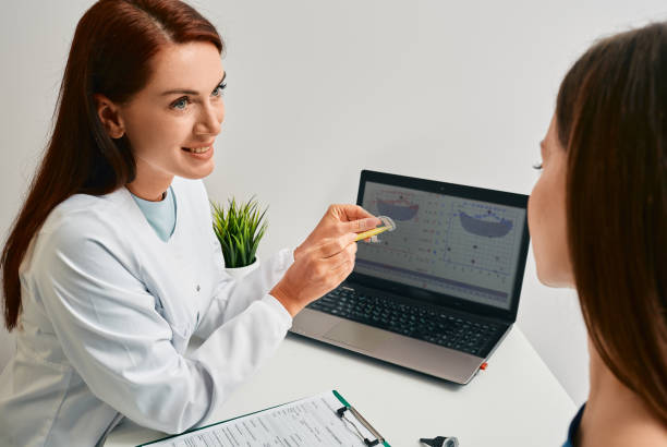 Audiologist advising patient to use BTE hearing aids to treat her deafness during consultation at hearing clinic. Audiology, hearing solutions stock photo