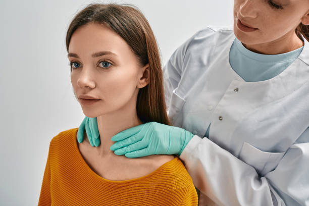 Endocrinologist checking thyroid gland of adult female patient by palpation. Woman has enlarged thyroid gland and hormones are not normal stock photo