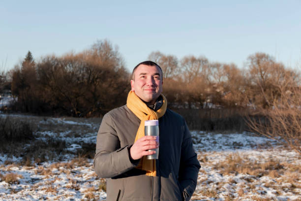 istock A man in nature in winter drinks hot tea from a mug. 1364165747
