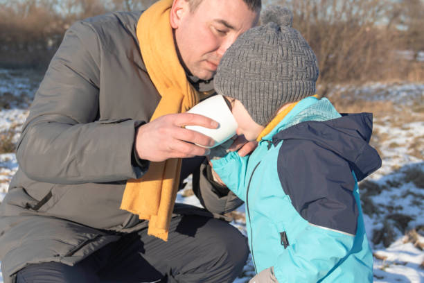 istock Dad and son in nature in winter drinking hot tea from a mug. 1364165896