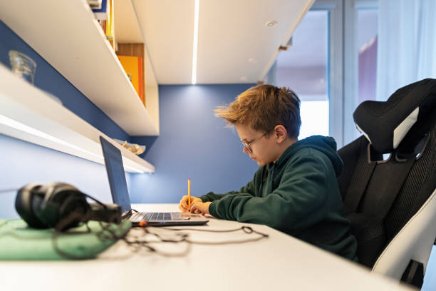 istock Little boy attending to online class in his room. 1364167619