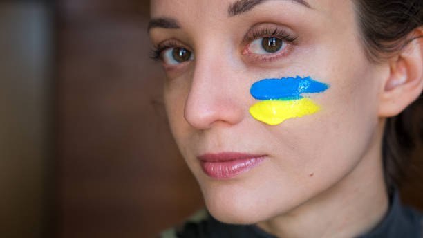 indoor portrait of young girl with blue and yellow ukrainian flag on her cheek wearing military uniform, mandatory conscription in ukraine, equality concepts - parade rest imagens e fotografias de stock