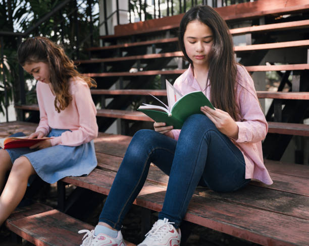 istock Student girl reading book at school park 1364167901