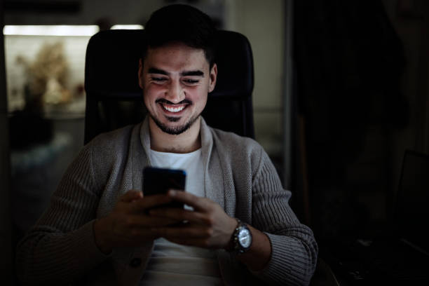 istock Smiling young man working on mobile phone at home. 1364170641