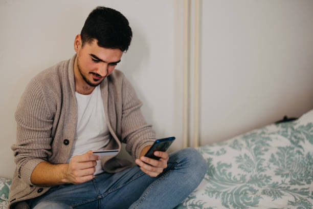 istock Young man e-banking with credit card at home. 1364170686