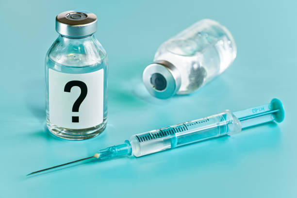 istock Vaccine bottle with hypodermic syringe needle near, question mark on label, another blurred vial cyan background 1364175132
