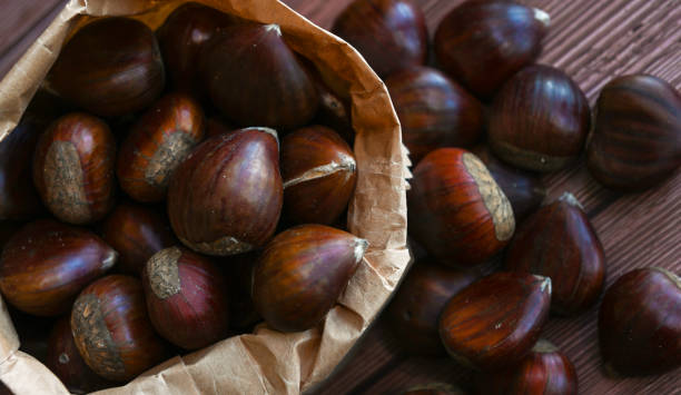istock Chestnuts in a paper bag on a wooden background 1364176568