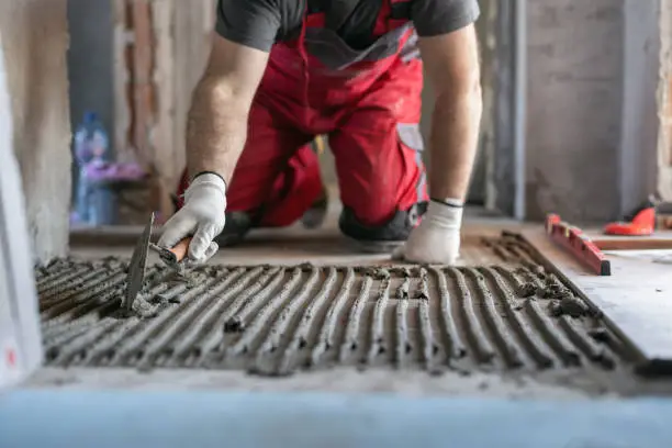 Photo of Worker applying tile adhesive on the floor