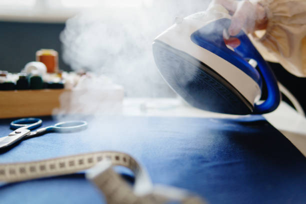 istock Woman ironing fabric on iron board with steaming iron. 1364177309