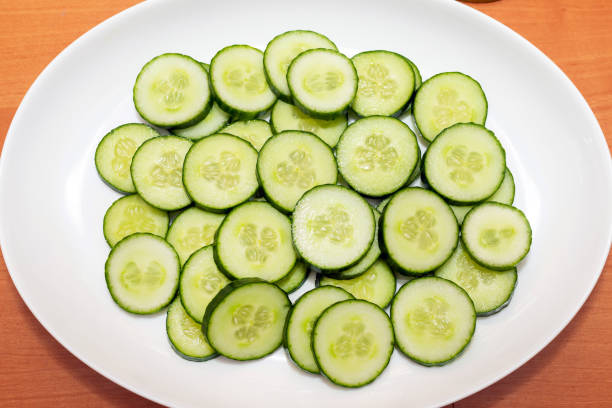 istock Sliced oval shape fresh cucumber Cucumis sativus in a white plate.Top view. 1364178800