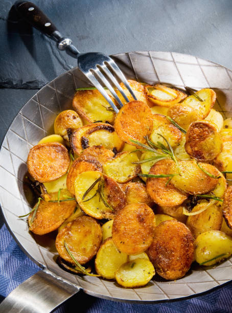 Roast potatoes in a cast iron pan Fried potatoes in a cast pan with rosemary fried potato stock pictures, royalty-free photos & images
