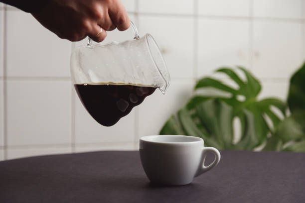 istock man's hand pouring coffee from glass coffee pot into a white cup. 1364184565