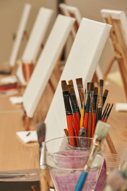 istock paint brushes and white canvases on easels 1364184799