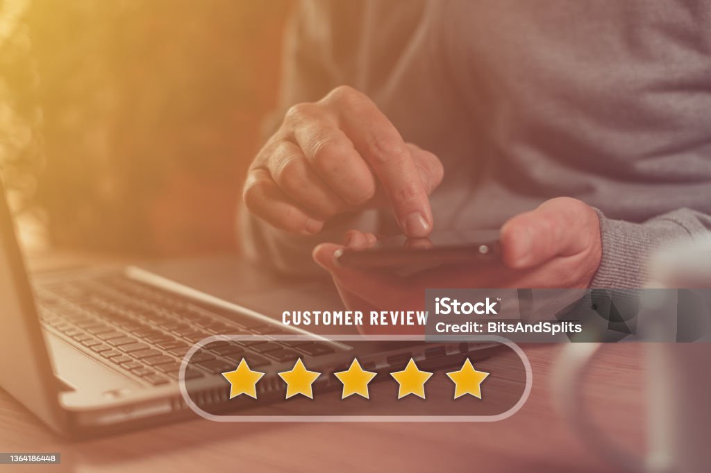 Customer review and five star rating concept, using smartphone and laptop for online service rate Customer review and five star rating concept, man using smartphone and laptop for online service rate, selective focus Feedback Stock Photo