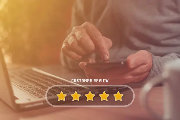 Customer review and five star rating concept, man using smartphone and laptop for online service rate, selective focus