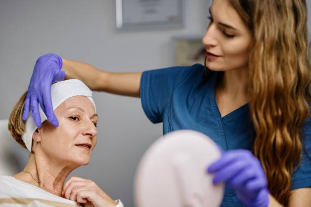 young female doctor talks about beauty treatments during a consultation with a mature woman patient - lifting device imagens e fotografias de stock