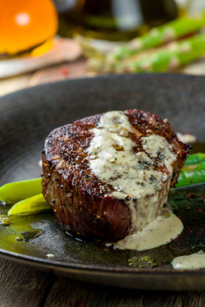 istock roast beef Steak with asparagus on black plate on wooden table macro close up, vertical 1364189819