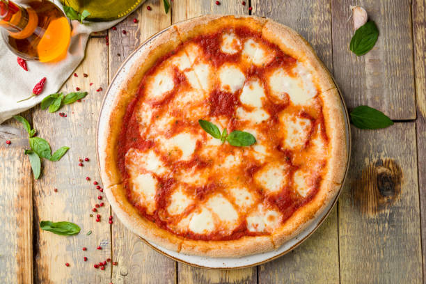 Italian pizza Margherita buffalo with tomatoes, mozzarella and basil on old wooden table top view stock photo