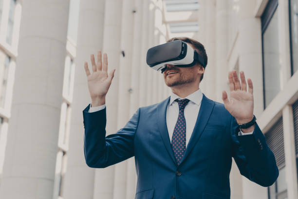 istock Businessman using VR headset for virtual reality game for work, standing outdoors 1364190081