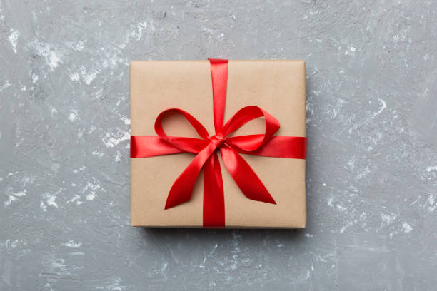 istock Holiday gift box wrapped in craft paper with colored bow on table background. Top view, flat lay, copy space 1364191581