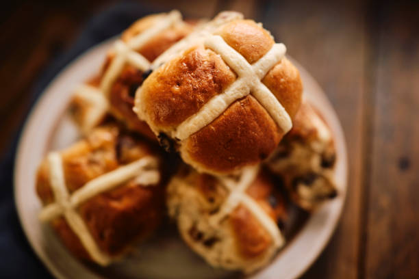 Overhead view of a plate of Hot Cross Buns on a rustic dark wooden table top. Overhead view of a plate of Hot Cross Buns on a rustic dark wooden table top. Hot Cross Bun stock pictures, royalty-free photos & images