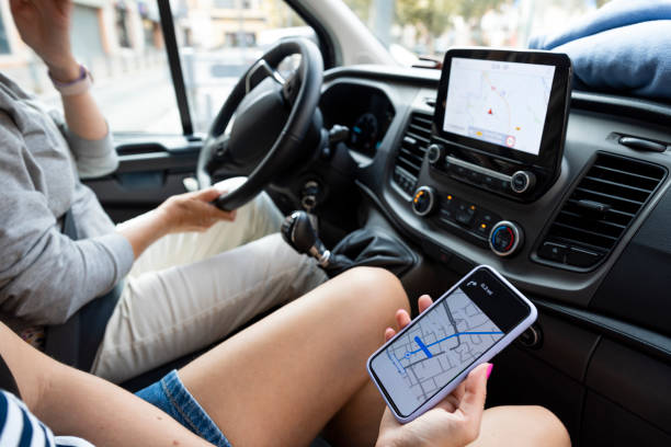 Looking Up the Way to Go Mother and daughter looking at a map on a smart phone while driving a rental van while on holiday in Castelferrus, France. family-van-driving stock pictures, royalty-free photos & images