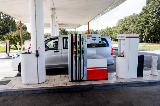 Rental van stopped at a petrol station while on holiday in France. There is a man sitting in the drivers seat.