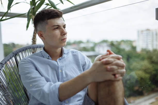 istock young man sitting on a chair on a balcony 1364199352