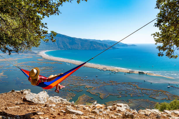 die frau, die in der hängematte liegt, schaut gerne auf den strand. - provinz mugla stock-fotos und bilder