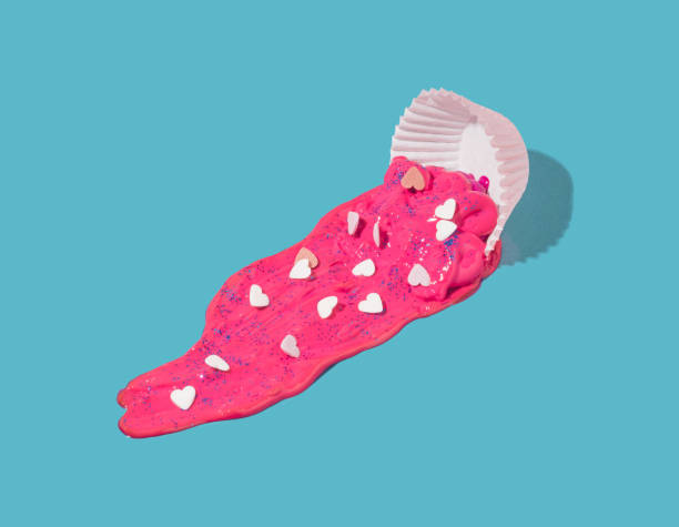 istock Cake cup with spilled pink pain with candy hearts on a pastel blue background. 1364202521