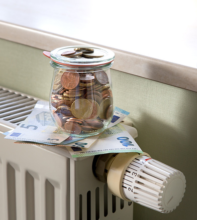 Mason jar full of euro coins and banknotes on a radiator