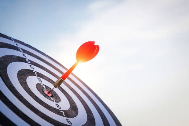 ダークブルーの空の背景にダーツボードセンターのターゲットにショット赤ダーツの矢印をクローズアップ。ビジネス目標または目標の成功と勝者の概念。 - determination expertise target bulls eye ストックフォトと画像