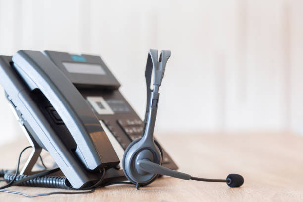 istock Communication support, call center and customer service help desk. VOIP headset on telephone keyboard. 1364202762