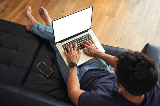 Man using laptop sitting on sofa with visible screen stock photo