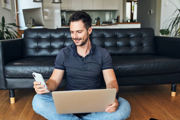istock Handsome man working at home using smartphone and laptop 1364206966