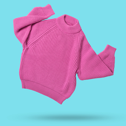 pink wool knitted sweater flies as if dancing, hands up, levitates on cyan background, shopping concept