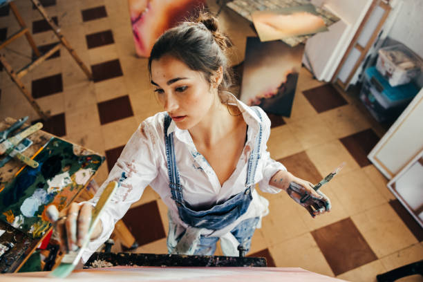istock Creative young artist painting with a paintbrush in her studio 1364210095