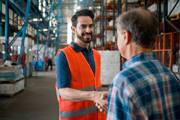 male employee shaking hands with manager in warehouse - polo shirt two people men working imagens e fotografias de stock