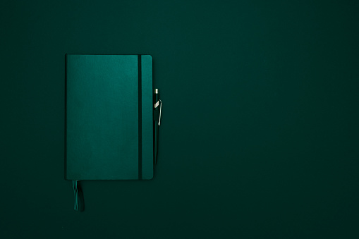 Top view of black photorealistic notebook on black background with green lights.