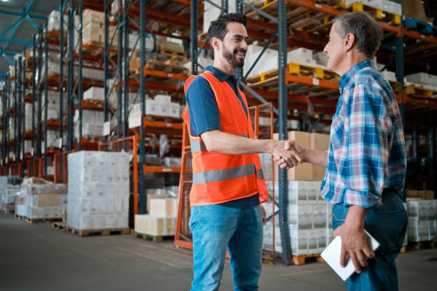 male worker shaking hands with manager in warehouse - polo shirt two people men working imagens e fotografias de stock