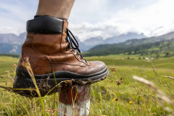Close-up of a  foot wearing a leather hiking shoe. Surrounded by scenic nature in the Dolomite Alps.