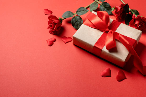 Valentines Day gifts, roses and confetti on red backdrop, copy space Red solid background with red hearts, gifts and confetti. The concept of Valentine Day. valentines present stock pictures, royalty-free photos & images