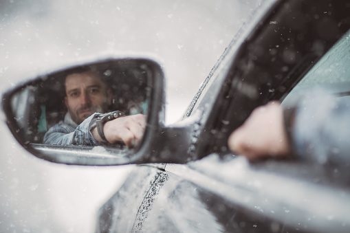 One man, a handsome young man traveling through a snow-covered forest, sits behind the wheel and enjoys a winter ride.