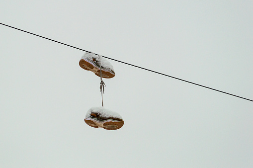 snow-covered sneakers hanging on wires. High quality photo