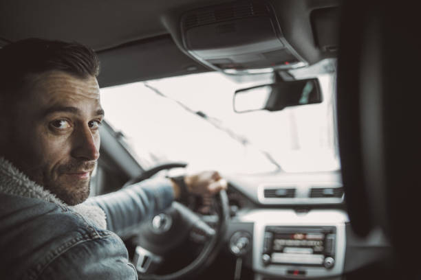 One man, a handsome young man traveling through a snow-covered forest, sits behind the wheel and enjoys a winter ride.